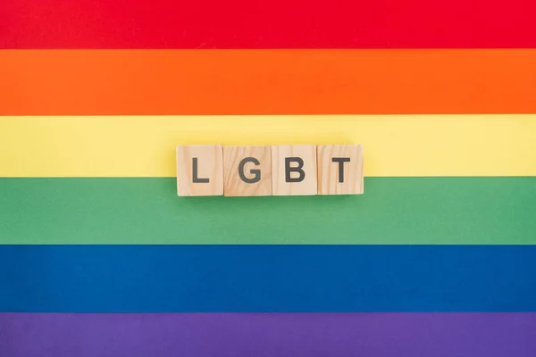 Top view of lgbt lettering made of wooden blocks on paper rainbow background — Stock Photo