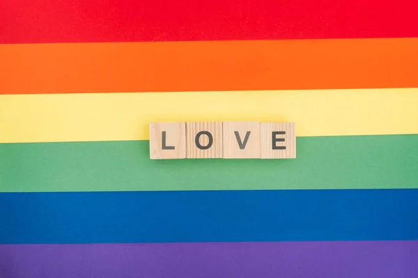 Vista superior do amor lettering feito de blocos de madeira sobre papel arco-íris fundo — Fotografia de Stock