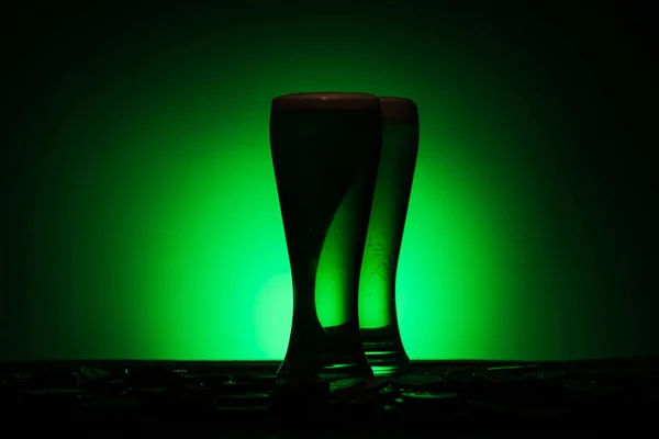 Silhouette of glasses of irish beer standing on table on green background — Stock Photo
