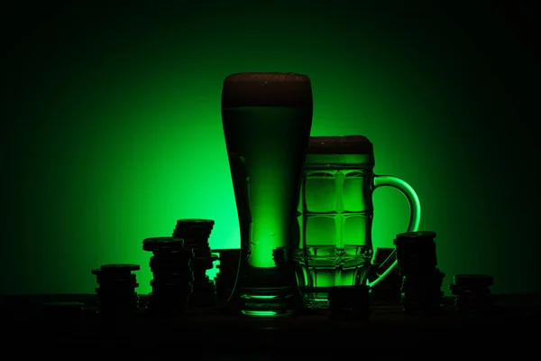 Silhueta de copos de cerveja irlandesa em pé na mesa perto de moedas no fundo verde — Fotografia de Stock