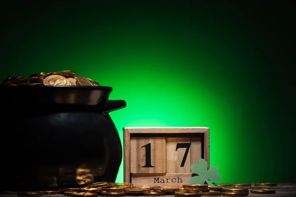 Cube calendar with date near golden coins in pot on green background — Stock Photo