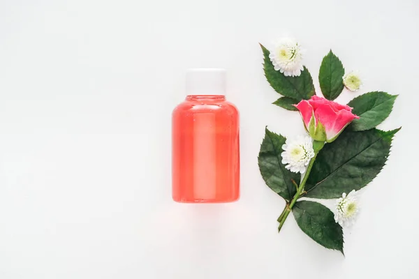 Top view of bottle with orange lotion near boutonniere isolated on white — Stock Photo