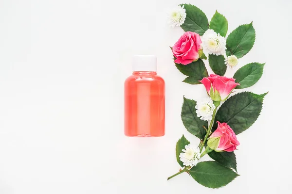 Top view of flowers composition and bottle with orange lotion isolated on white — Stock Photo