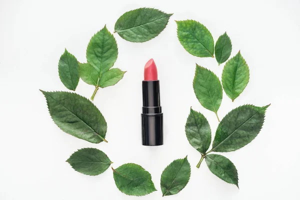 Top view of pink lipstick surrounded rose leaves isolated on white — Stock Photo