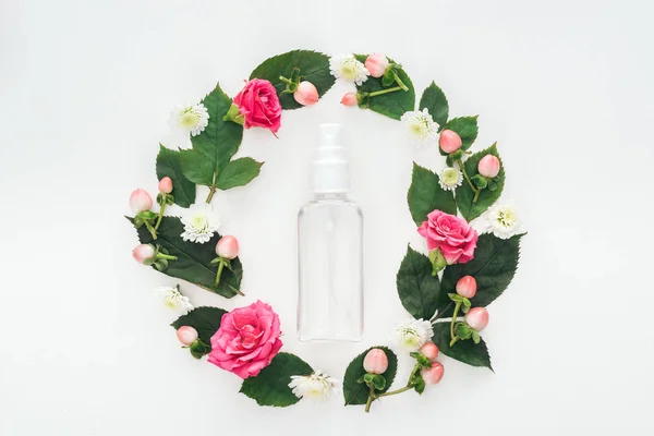 Vista superior de composición circular con hojas verdes, flores y botella de spray vacía aislada en blanco - foto de stock