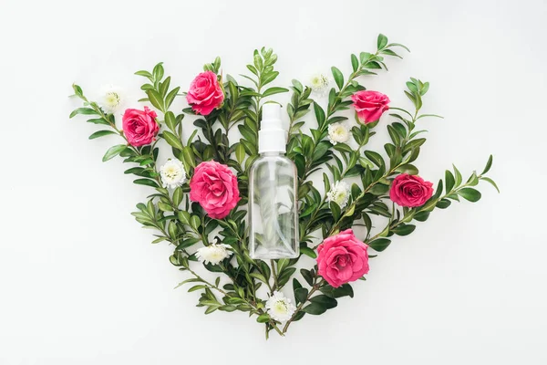 Vista superior da composição de flores com rosas rosa, buxo verde e frasco de spray vazio no fundo branco — Fotografia de Stock