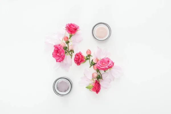 Vista dall'alto della composizione con boccioli di rose, bacche, petali e bottiglie cosmetiche su sfondo bianco — Foto stock
