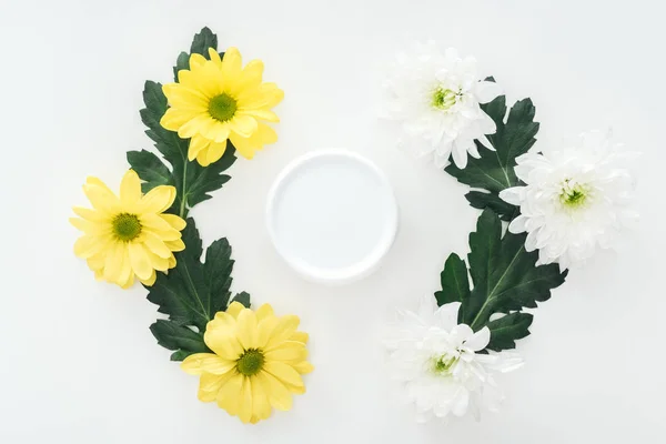Vue du dessus des compositions avec chrysanthèmes et crème de beauté en bouteille sur fond blanc — Photo de stock
