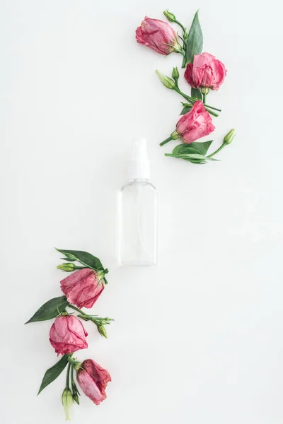 Вид сверху на розовую эустому и пустую бутылку с брызгами на белом фоне — стоковое фото