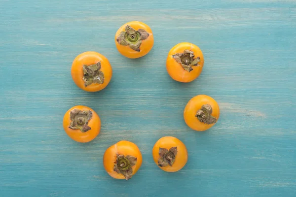 Circle of juicy whole orange persimmons with copy space — Stock Photo