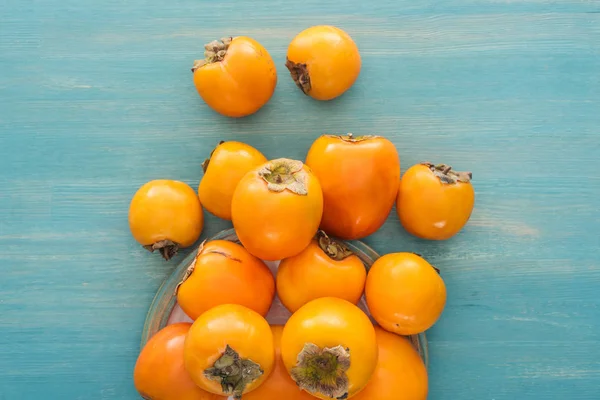 Vista superior de caquis maduros de color naranja sobre fondo azul - foto de stock