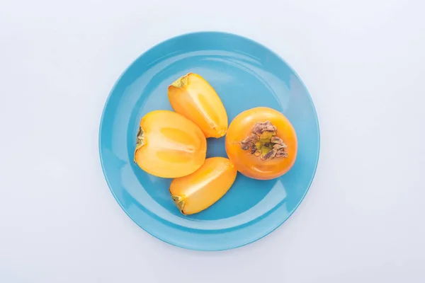 Top view of sweet cut and whole persimmons on blue glass plate — Stock Photo