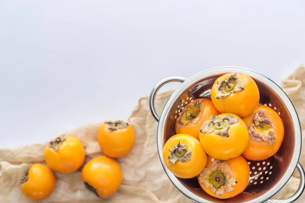 Selective focus of persimmons in colander with copy space on white background — Stock Photo