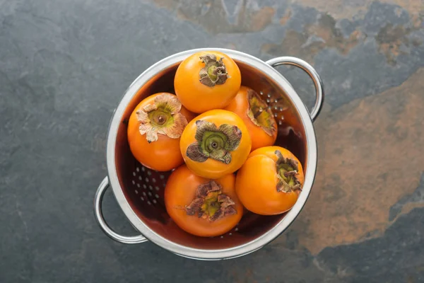 Draufsicht auf reife, leckere Orangen-Kaki im Sieb — Stockfoto