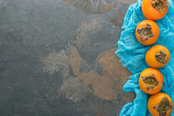 Ansicht ganzer Persimmons auf blauem Tuch mit Kopierraum — Stockfoto