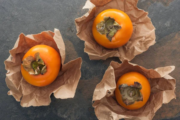 Vista superior de laranja e cáqui inteiros em papel — Fotografia de Stock