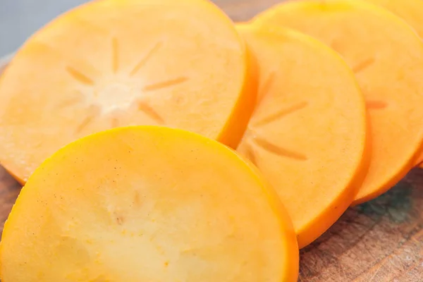 Close-up de fatias de caqui de corte laranja em tábua de madeira — Fotografia de Stock