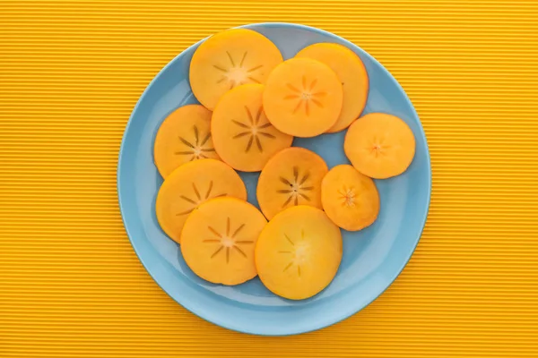 Aufgeschnittene und orangefarbene Kaki auf blauem Teller — Stockfoto