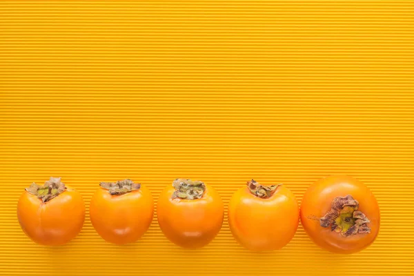 Top view of orange persimmons on yellow background  with copy space — Stock Photo