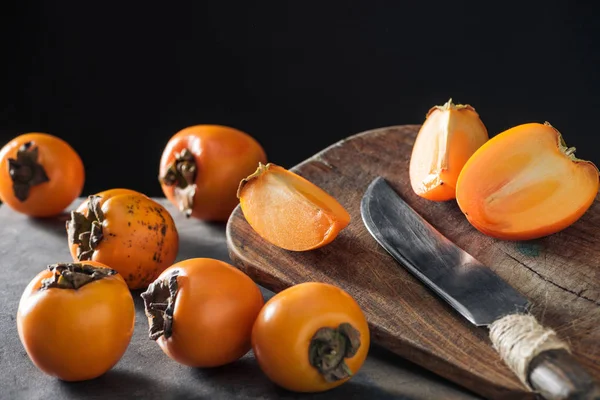 Cáqui maduro e laranja na tábua de corte com faca — Fotografia de Stock