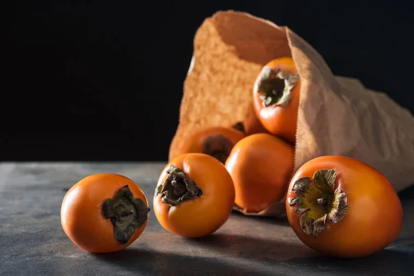 Foco seletivo de cáqui laranja em pacote de papel isolado em preto — Fotografia de Stock