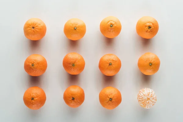 Tendido plano con mandarinas sin pelar y pelado uno sobre fondo blanco - foto de stock