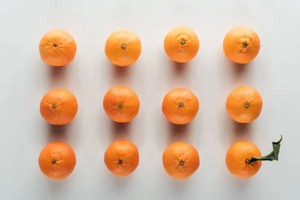 Flat lay with bright ripe orange tangerines and one with green leaves — Stock Photo