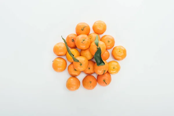 Top view of bright ripe orange tangerines with green leaves stacked in pile on white background — Stock Photo