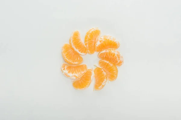 Plat étendu avec des tranches de mandarine pelées disposées en cercle sur fond blanc — Photo de stock