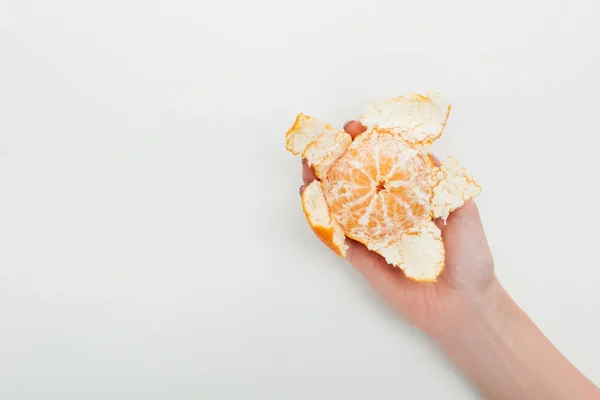 Vista recortada de la mujer sosteniendo mandarina naranja madura con cáscara sobre fondo blanco - foto de stock