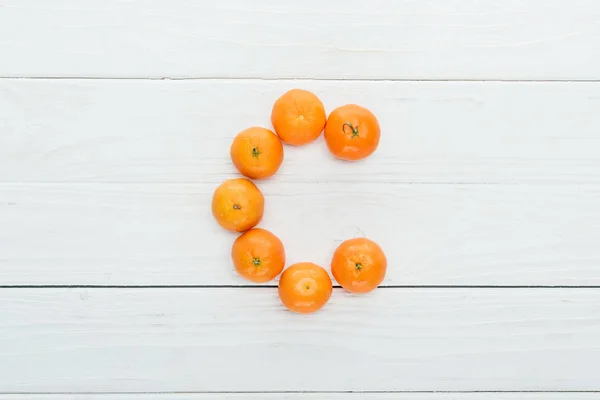 Top view of letter c made of fresh tangerines on wooden white background — Stock Photo