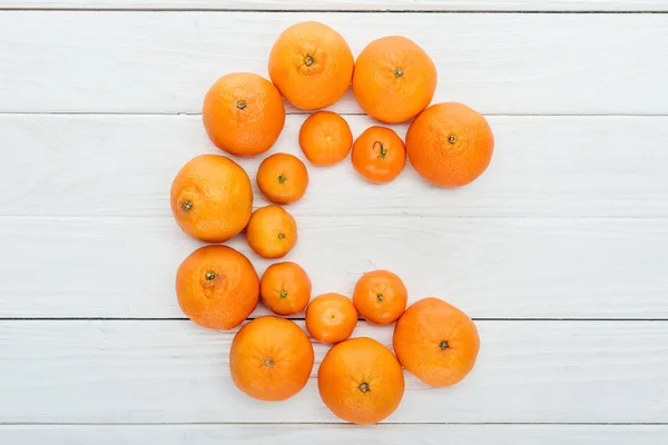 Vista superior de la letra C hecha de mandarinas frescas en la superficie blanca de madera - foto de stock