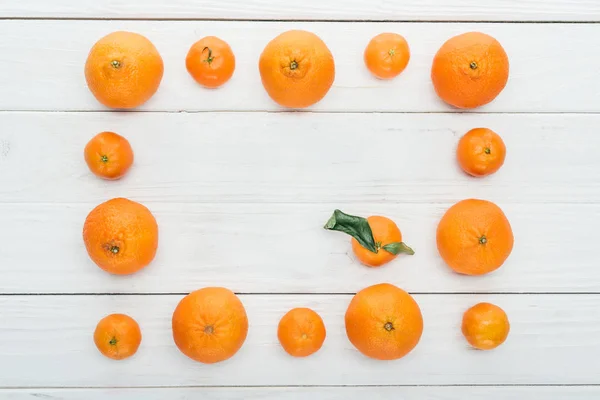 Top view of square frame made of ripe orange tangerines on wooden white background — Stock Photo