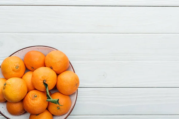 Draufsicht auf reife orange Mandarinen im Teller auf weißem Holzhintergrund — Stockfoto