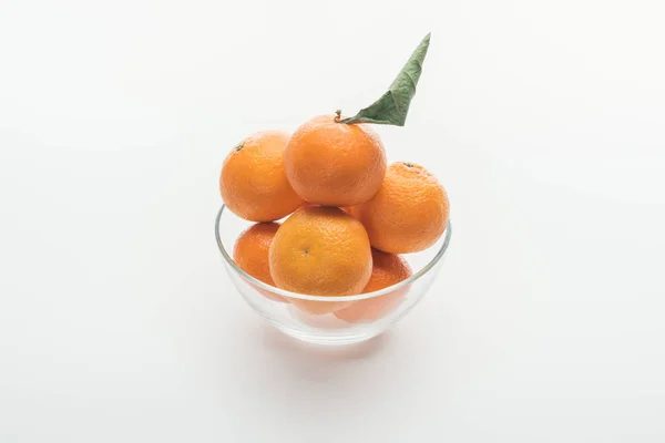 Tazón de cristal lleno de mandarinas enteras naranjas maduras sobre fondo blanco - foto de stock