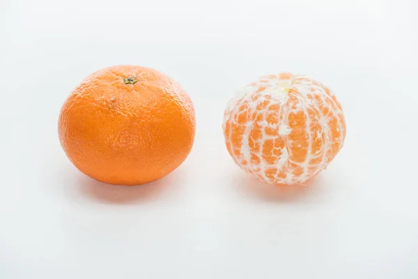 Ripe orange whole peeled and unpeeled tangerines on white background — Stock Photo