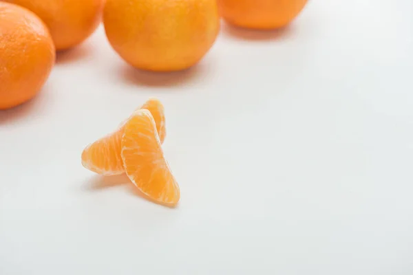 Enfoque selectivo de rodajas de mandarina naranja madura sobre fondo blanco - foto de stock