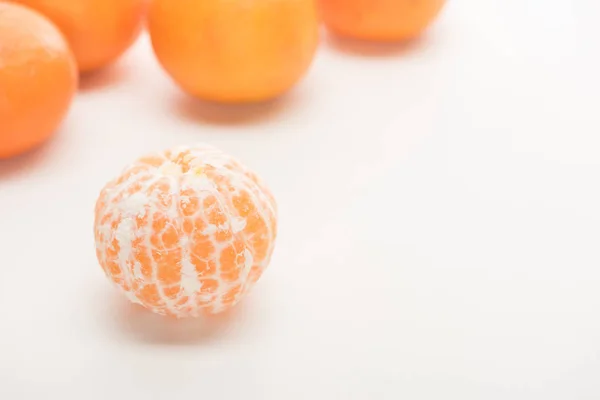 Selective focus of ripe peeled whole tangerine on white background — Stock Photo