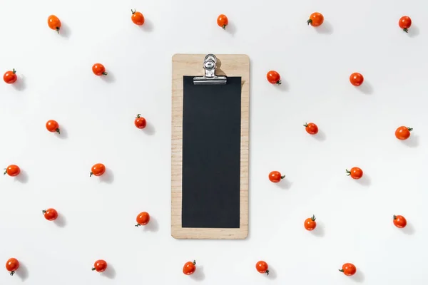 Vue du dessus du presse-papiers vide avec tomates cerises sur fond blanc — Photo de stock