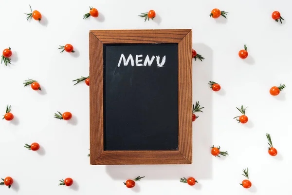 Kreidetafel mit Menüaufdruck zwischen Kirschtomaten und -blättern — Stockfoto