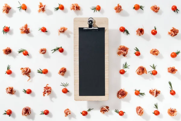 Top view of empty clipboard with cherry tomatoes, leaves and prosciutto — Stock Photo