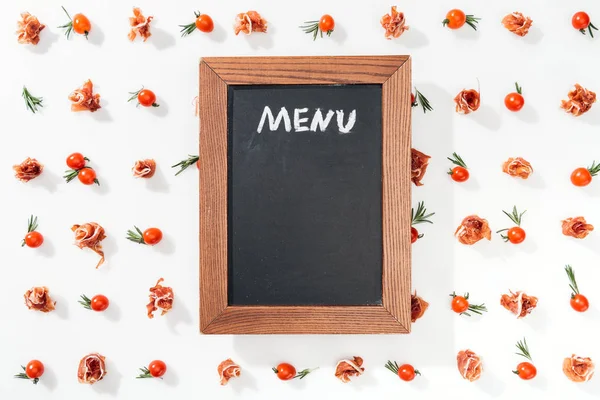 Kreidetafel mit Menüaufdruck zwischen Kirschtomaten, Schinken und Blättern — Stockfoto