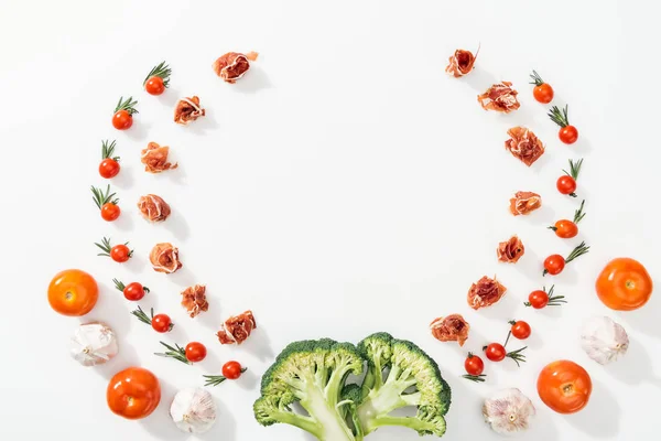 Top view of tomatoes, leaves, prosciutto, broccoli and garlic with copy space — Stock Photo