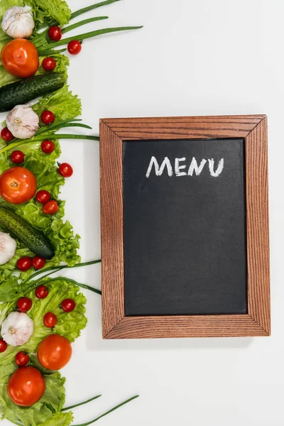 Vue du dessus de la planche à craie avec lettrage de menu parmi les tomates, feuilles de laitue, concombres, oignon et ail — Photo de stock