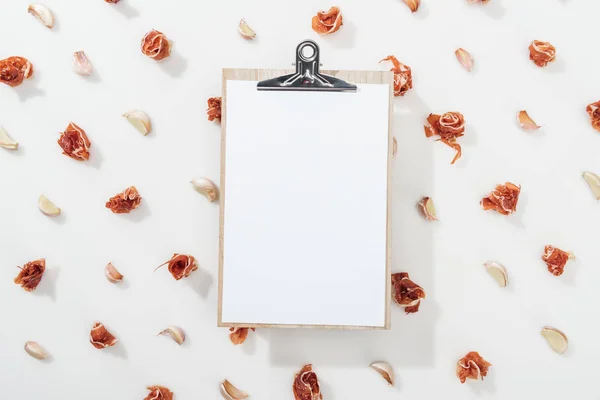 Top view of clipboard among prosciutto and garlic cloves — Stock Photo