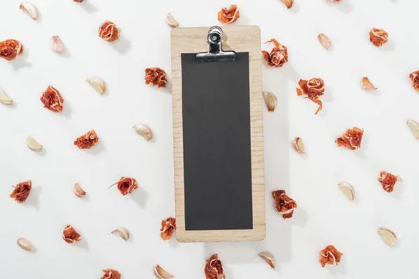 Top view of empty clipboard among prosciutto and garlic cloves — Stock Photo