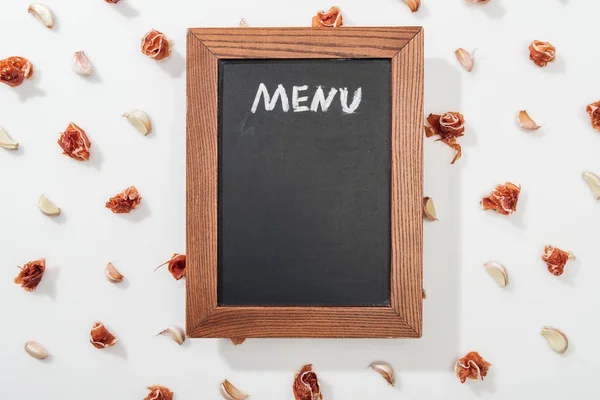 Vista superior de pizarra con letras de menú entre jamón y dientes de ajo - foto de stock