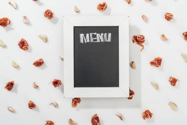 Top view of chalk board with menu lettering among prosciutto and garlic cloves — Stock Photo