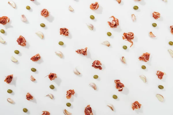 Draufsicht auf Prosciutto, Oliven und Knoblauchzehen auf weißem Hintergrund — Stockfoto