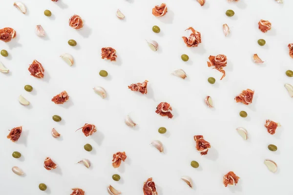 Top view of prosciutto, olives and garlic cloves on white background — Stock Photo